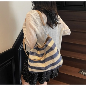 Detail of blue and white striped woven tote bag with leather and silver chain straps