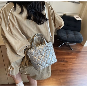 Detail of silver quilted bucket bag with metallic rivets and stylish crossbody strap