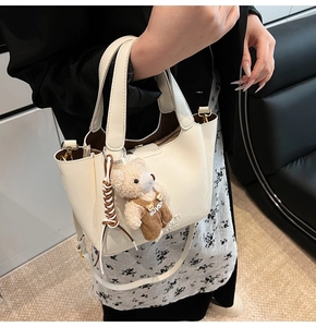 Detail of cream leather bucket bag with cute bear charm and adjustable shoulder strap