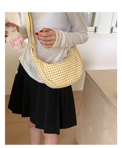 Detail of a yellow and white checkered dumpling bag with adjustable shoulder strap on a model
