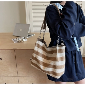 Detail of contrast woven tote bag with chain strap and summer bohemian stripe texture
