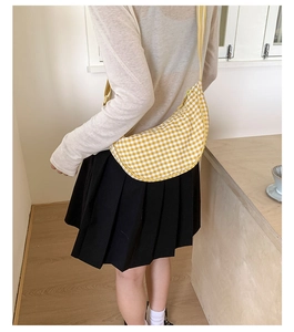 Detail of yellow plaid dumpling bag featuring woven texture and striped strap