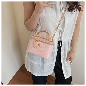 Detail of pink ostrich texture handbag with gold metal handle and chain strap on a model
