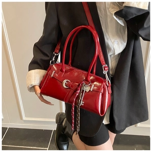Détail d'un sac à main rouge en cuir verni avec pendentif coeur sur modèle