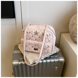 Close-up of pink quilted faux leather bag with silver rivets and star emblem detail