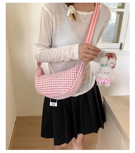 Pink checkered croissant bag with a cute plush bunny charm worn by a model