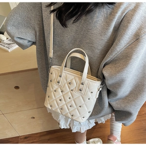 Detail of cream quilted bucket bag with silver studs and adjustable shoulder strap