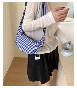 Detail view of the blue and white gingham crescent bag with striped webbing strap