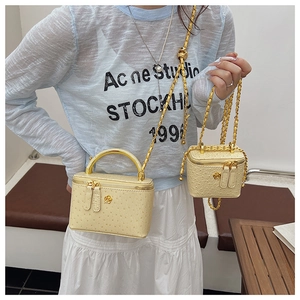 Detailed view of yellow ostrich texture leather handbags with golden chain and flower logo
