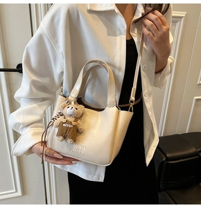 Detail of off-white faux leather bucket bag with teddy bear charm and logo embossing