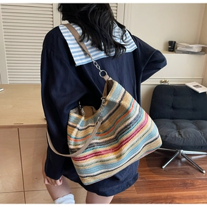 Close-up of a large woven tote bag featuring colorful horizontal stripes and a chain strap