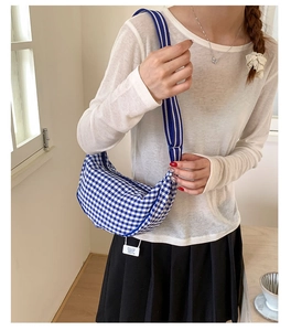 Detailed view of the blue and white gingham dumpling bag with wide striped shoulder strap