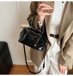 Gros plan du sac Boston en cuir verni noir avec lettrage MUSETI SHI SHANG embossé chic