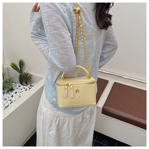 Detail of light yellow ostrich texture box bag with camellia ornament and gold handle