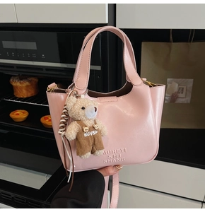 Detail view of pink oil wax leather bucket bag with a cute bear plush keychain accessory