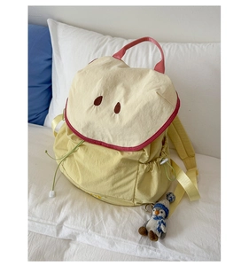 Detail of macaron yellow waterproof nylon backpack with plush penguin charm and embroidery