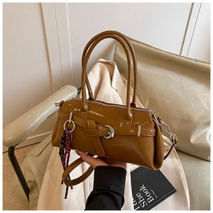 Détail d'un sac à main marron en cuir brillant avec boucle argentée et foulard en soie à carreaux