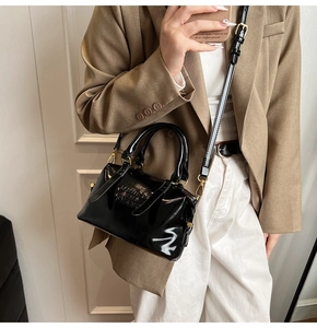 Vue détaillée du sac Boston en cuir verni noir avec logo gaufré et détails dorés