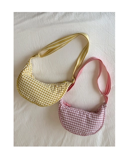Detail view of yellow and pink gingham crescent crossbody bags with striped straps