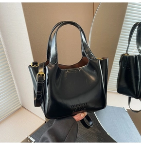 Close-up of black oil-wax leather bucket bag with embossed logo and metallic buckle detail