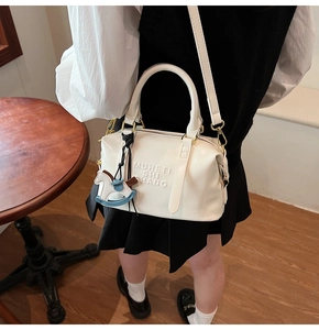 Détail du sac Boston blanc avec lettrage embossé et petit pendentif en forme de cheval