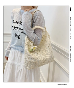 Detailed view of cream lace tote bag with floral patterns and a daisy charm accessory