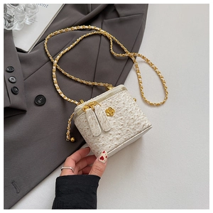 Macro shot of white ostrich skin texture handbag with golden chain and floral charm