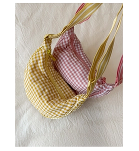 Detail of yellow and pink plaid half-moon crossbody bags with fabric texture and zippers
