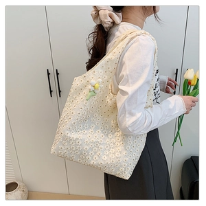 Close-up of white lace tote bag featuring 3D floral embroidery and a cute flower charm