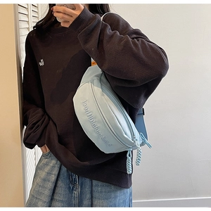 Détail du sac bandoulière bleu clair avec lettres gaufrées et tirette de zip tressée