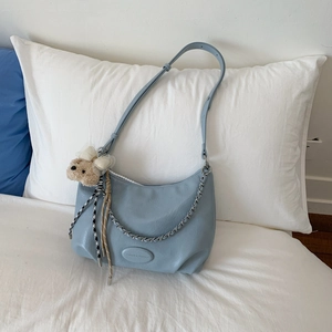 Close-up of soft blue PU leather bag with silver chain detail and small bear charm