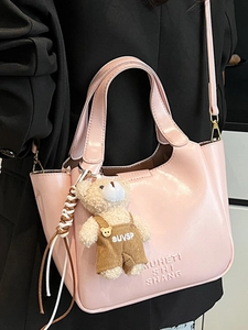 Pink oily leather bucket bag with cute bear charm and embossed fashion text detail