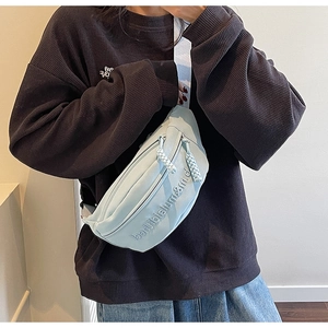 Gros plan d'un sac de poitrine en toile bleu clair avec broderie et tirettes tressées
