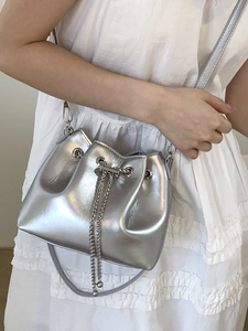 Minimalist silver bucket bag with metallic mirror finish and silver chain shoulder strap