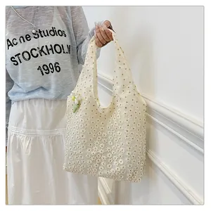 Detail of white daisy embroidery on lace hollow tote bag with floral charm