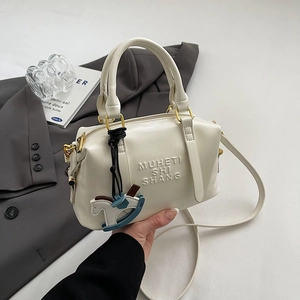 Détail du sac Boston blanc cassé avec lettrage embossé et pendentif en forme de cheval