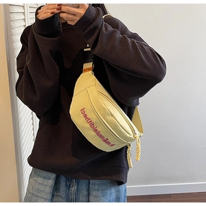 Gros plan d'un sac de poitrine en toile beige avec broderie rouge et sangle ajustable