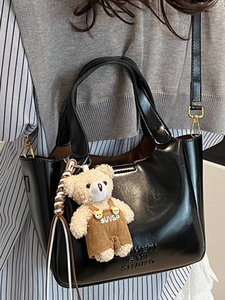 Minimalist black oil wax leather bucket bag with cute brown teddy bear charm accessory