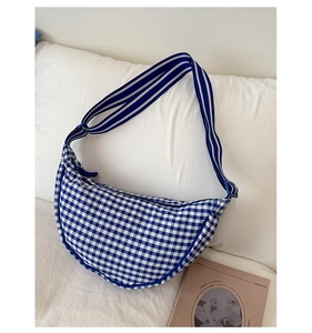 Detail view of the blue gingham crescent bag with striped strap on a soft background