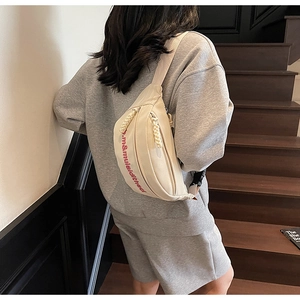 Détail de la bandoulière réglable et de la boucle en plastique du sac bandoulière crème