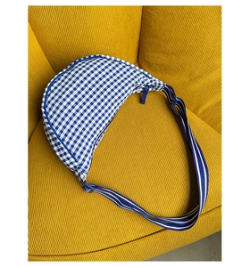 Macro shot of blue vichy checkered pattern on a canvas half-moon bag with fabric strap