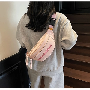 Détail du sac bandoulière en nylon rose avec broderie de qualité et tirettes de zip tissées