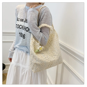 Detailed close-up of a white floral lace tote bag featuring an 3D daisy flower charm