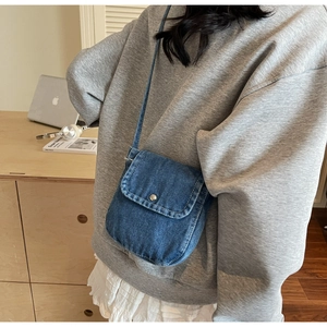 Detailed shot of a blue denim mini crossbody bag with silver round snap button closure