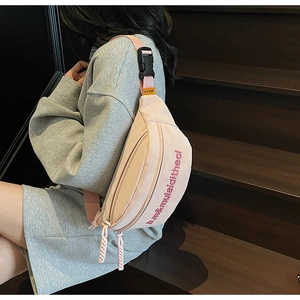 Détail du sac bandoulière rose en toile avec broderie rouge et étiquette MULAIDI