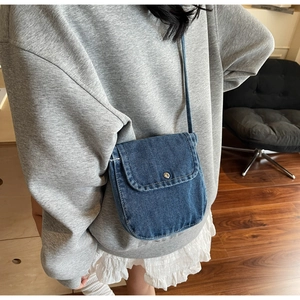 Detail shot of mini vintage blue denim crossbody bag with flap and metal button