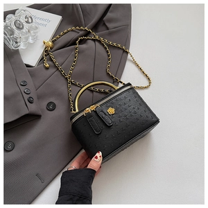 Detail of black ostrich texture box bag with golden camellia and metal handle
