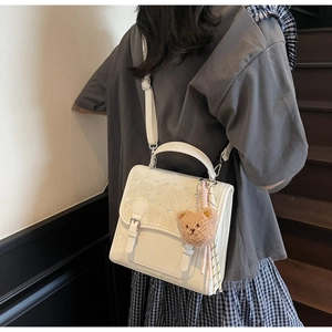 Detailed view of white PU leather bag with sparkling rhinestones and cute bear pendant