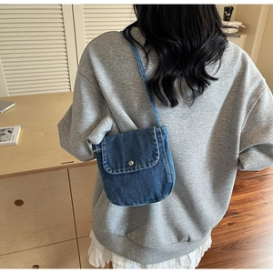 Detail of vintage denim crossbody bag showing metal button closure and contrast stitching