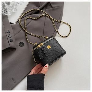 Detail of black ostrich texture bag with gold flower logo and metal chain strap